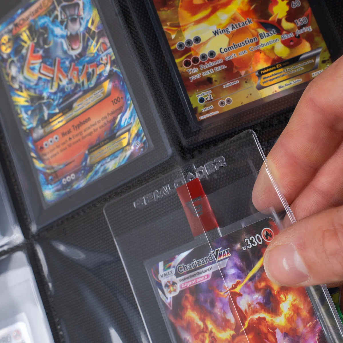 A hand slides a Charizard VMAX Pokémon card in a semi-rigid sleeve into the Gemloader: Premium Semi-Rigid Samlemappe [168 pockets 2X3] by Gemloader, with other cards like Mega Typhlosion EX visible in nearby slots.