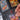 A hand slides a Charizard VMAX Pokémon card in a semi-rigid sleeve into the Gemloader: Premium Semi-Rigid Samlemappe [168 pockets 2X3] by Gemloader, with other cards like Mega Typhlosion EX visible in nearby slots.
