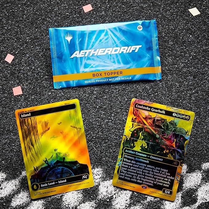 A Magic the Gathering: Aetherdrift Collector Booster Box by Wizards of the Coast rests on a textured surface, with Island and Coalskin Gearhulk cards shown below and confetti scattered nearby.